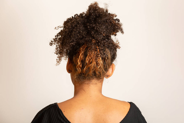 Young black woman on her back with afro hairstyle on white background. Girl with african hairstyle. Studio shot. - Photo, Image