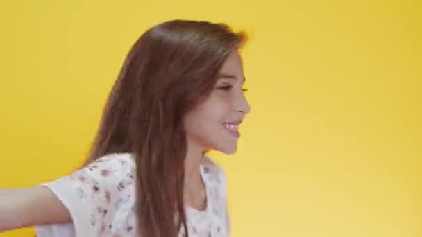 Cute caucasian girl with long hair posing and gesturing on yellow background - Video, Çekim