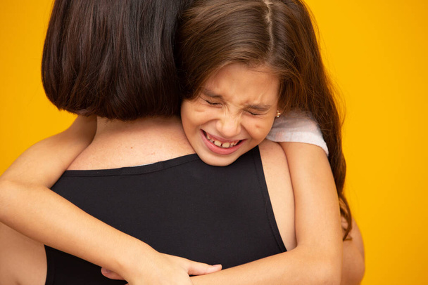 Πορτρέτο ενός μικρού κοριτσιού που κλαίει και το κρατάει η μητέρα της. - Φωτογραφία, εικόνα