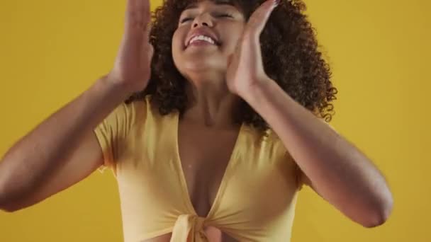 Young brazil curly woman gesturing and posing on yellow background - Filmmaterial, Video