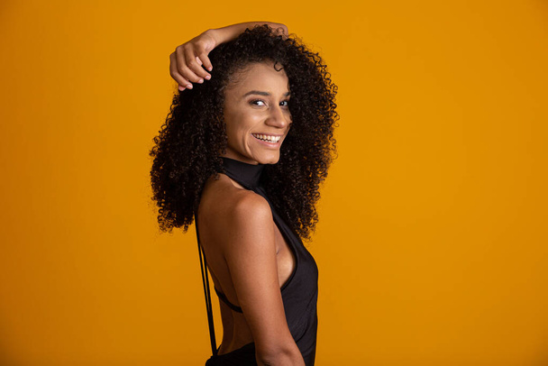 Mujer afroamericana joven con el pelo rizado mirando a la cámara y sonriendo. Linda chica afro con el pelo rizado sonriendo mirando a la cámara
. - Foto, imagen
