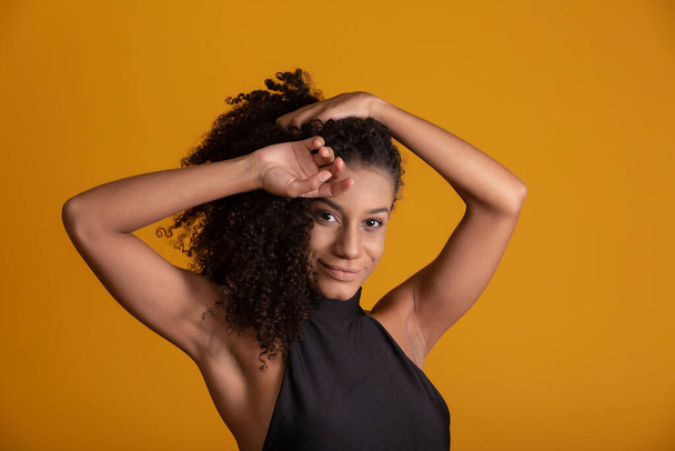 Young afro-american woman with curly hair looking at camera and smiling. Cute afro girl with curly hair smiling looking at camera. - Photo, Image