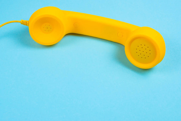 Yellow handset on a blue background. Copy space. - Photo, Image