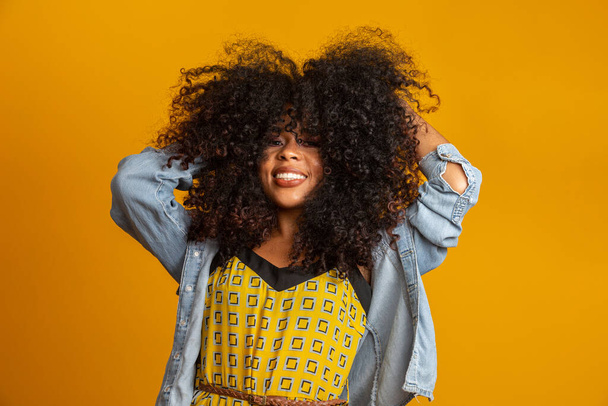 Beauty portrait of african american woman with afro hairstyle and glamour makeup. Brazilian woman. Mixed race. Curly hair. Hair style. Yellow background. - Foto, Bild