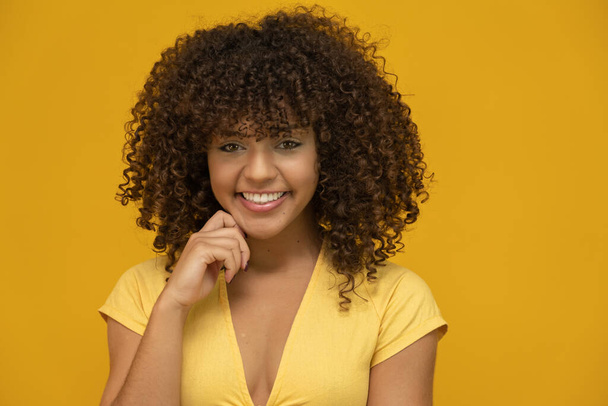 Giovane donna riccia latina in posa su sfondo giallo brillante
 - Foto, immagini