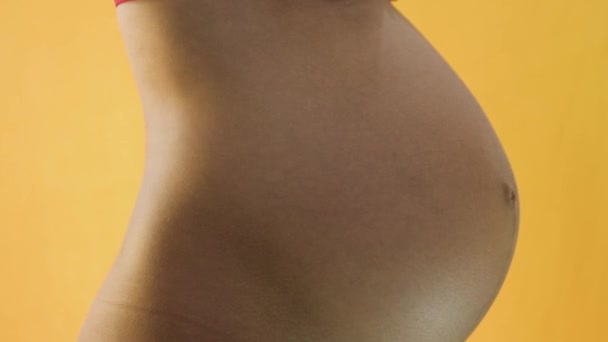 Kobieta w ciąży pozująca na żółtym tle - Materiał filmowy, wideo
