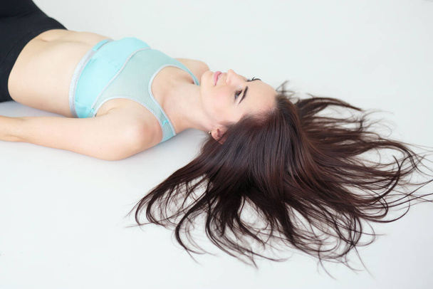 Young woman with pretty hairstyle wearing sportswear lying on the floor - Foto, immagini