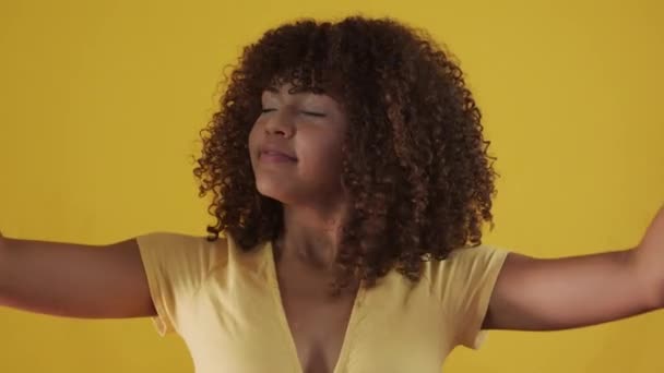 Young brazil curly woman gesturing and posing on yellow background - Filmagem, Vídeo
