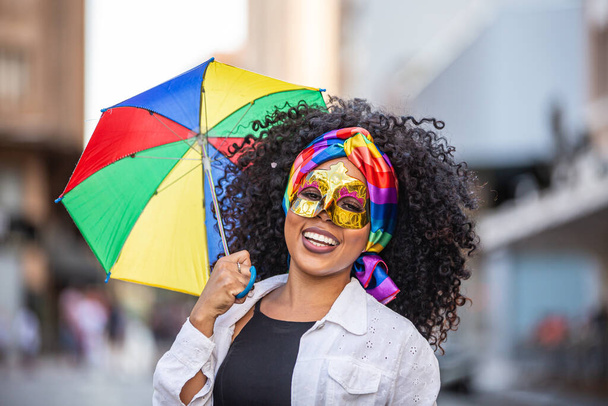 Jovem mulher cabelo encaracolado comemorando a festa de carnaval brasileira com guarda-chuva Frevo na rua
. - Foto, Imagem