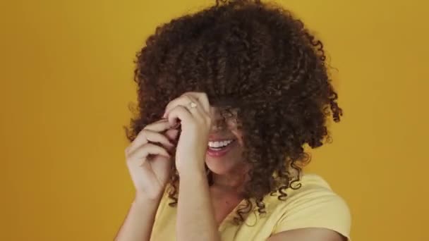 Young brazil curly woman gesturing and posing on yellow background - Záběry, video