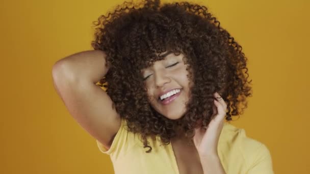 Young brazil curly woman gesturing and posing on yellow background - Felvétel, videó