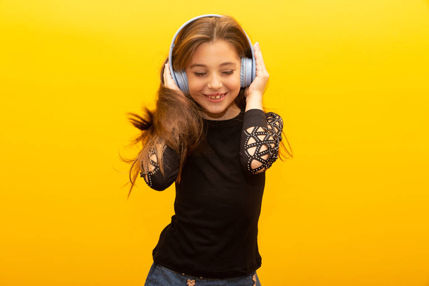 Girl enjoying music wearing headset and dancing - Фото, изображение