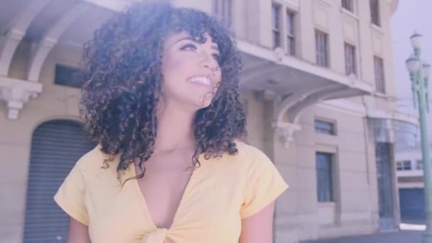 Stylish curly woman posing on city background - Filmati, video