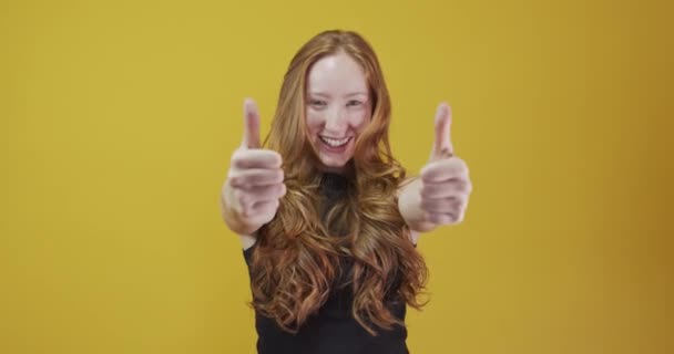 Redhead young woman posing gesturing on yellow background - Záběry, video