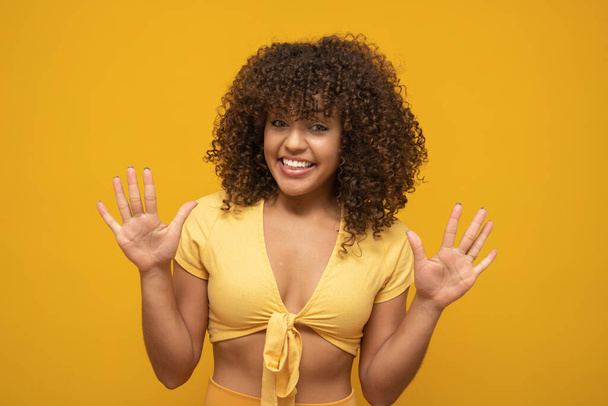 Young latin curly woman posing on bright yellow background - Фото, изображение