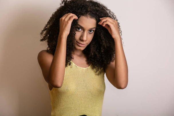 Fiatal afro-amerikai nő göndör hajjal, kamerába néz és mosolyog. Aranyos afro lány göndör haj mosolygós nézi kamera. - Fotó, kép