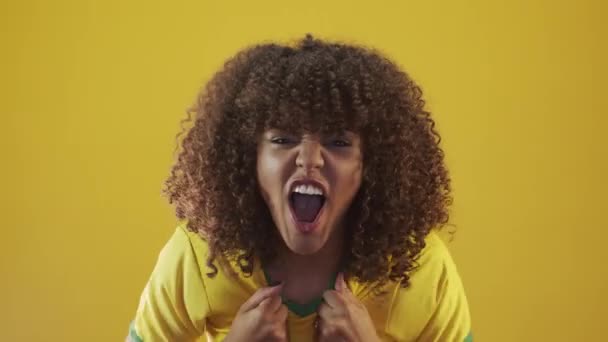 Young brazil curly woman gesturing and posing on yellow background - Materiał filmowy, wideo