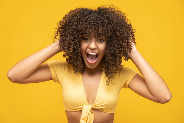 Young latin curly woman posing on bright yellow background - Photo, Image