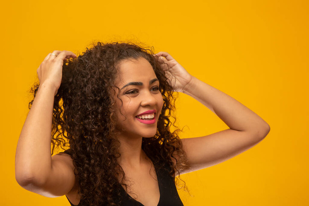 Gyönyörű fiatal nő göndör haj sárga háttér - Fotó, kép