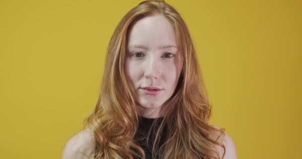 Ruda młoda kobieta pozowanie gestykulacji na żółtym tle - Materiał filmowy, wideo
