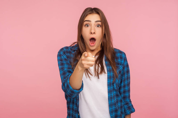 Wow, hey you! Portrait of astonished girl in checkered shirt pointing to camera, standing with surprised shocked expression on face, hard to believe. indoor studio shot isolated on pink background - Foto, Bild