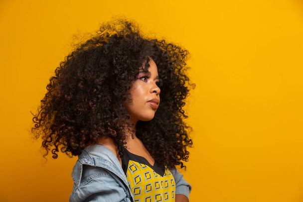 Beauty portrait of african american woman with afro hairstyle and glamour makeup. Brazilian woman. Mixed race. Curly hair. Hair style. Yellow background. - Φωτογραφία, εικόνα