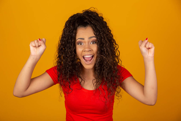 Beautiful African American young woman happy and excited celebrating victory expressing big success, power, energy and positive emotions. Celebrates new job joyful. - Fotografie, Obrázek