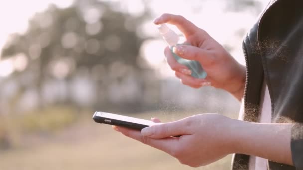 La mujer está rociando antiséptico en una pantalla del teléfono
 - Imágenes, Vídeo