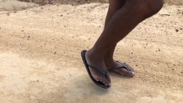 Közeli kép fekete ember sétál a földön papucsban - Felvétel, videó