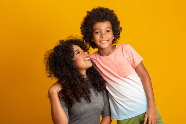 Портрет молодой афроамериканской матери с маленьким сыном. Желтый фон. Бразильцы
. - Фото, изображение