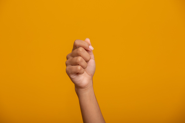 Woman hand holding something on yellow background, closeup of hand. - Foto, Bild