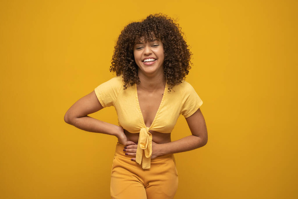 Young latin curly woman posing on bright yellow background - Фото, зображення