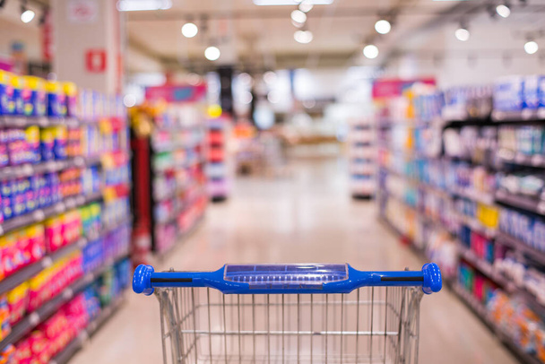 Carrinho de compras vista no corredor do supermercado com prateleiras de produtos borrão abstrato desfocado fundo
 - Foto, Imagem