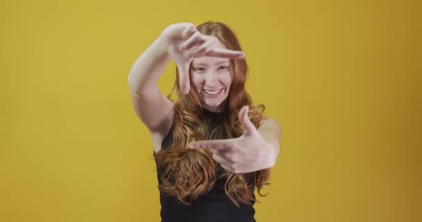 roodharige jonge vrouw poseren gebaar op gele achtergrond - Video