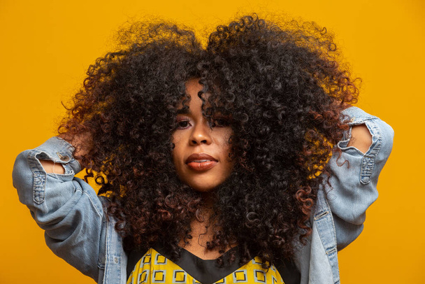 Beauty portrait of african american woman with afro hairstyle and glamour makeup. Brazilian woman. Mixed race. Curly hair. Hair style. Yellow background. - Foto, immagini