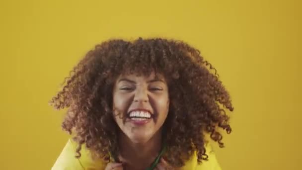 Young brazil curly woman gesturing and posing on yellow background - 映像、動画