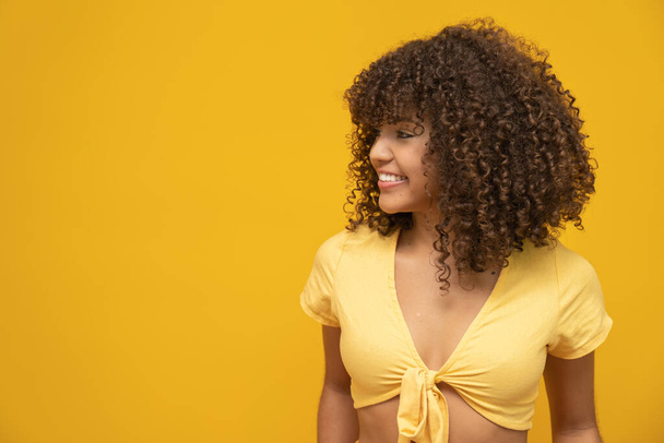 Young latin curly woman posing on bright yellow background - Fotoğraf, Görsel