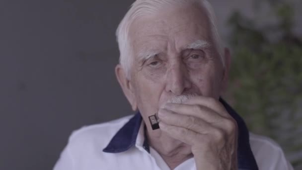 Nahaufnahme eines alten Mannes, der Mundharmonika spielt - Filmmaterial, Video