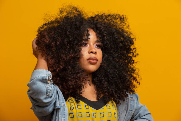 Beauty portrait of african american woman with afro hairstyle and glamour makeup. Brazilian woman. Mixed race. Curly hair. Hair style. Yellow background. - Foto, Imagen