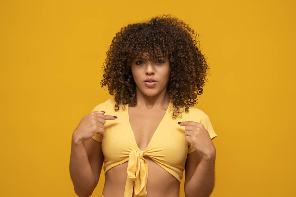 Jeune femme bouclée latine posant sur fond jaune vif
 - Photo, image