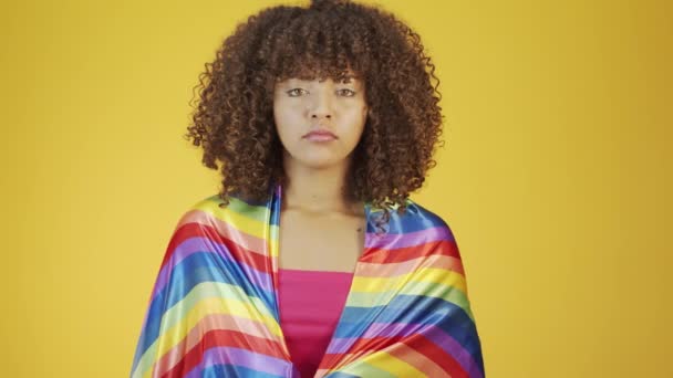 Молода бразилія кучерява жінка жестикулює і позує з веселкою ЛГБТ прапором на жовтому тлі
 - Кадри, відео