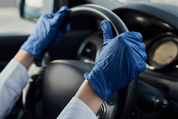 Driver driving a car in medicine protective gloves. Coronavirus covid-19 protection concept - Zdjęcie, obraz