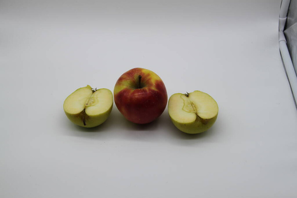manzanas enteras y cortadas doradas y rojas en mitades sobre fondo blanco
 - Foto, Imagen