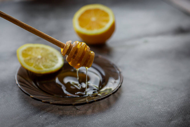 miel dégoulinant sur une soucoupe, fond gris avec du citron
 - Photo, image