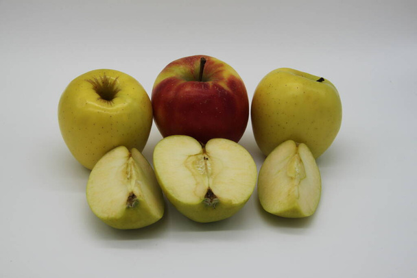 manzanas doradas y rojas enteras y cortadas en cuartos y medio sobre fondo blanco
 - Foto, Imagen
