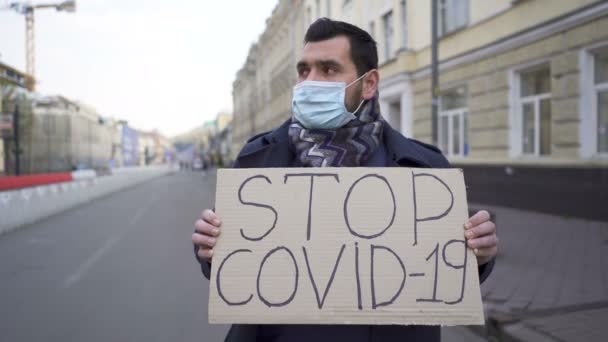  Людина в медичній масці виступає протестом з плакатом на міській вулиці. Команда пандемії слова
 - Кадри, відео