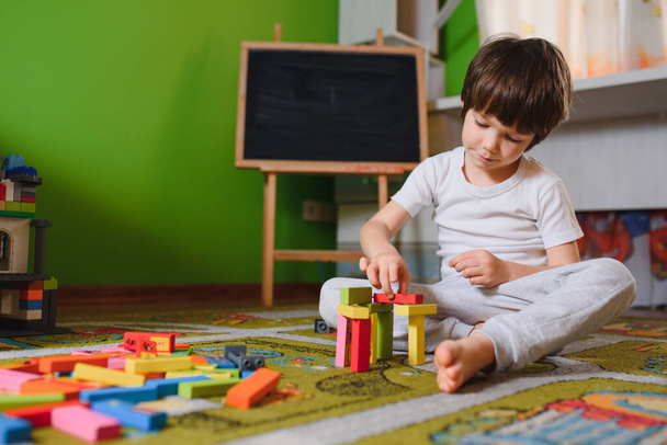child little boy playing with wooden cubes toys in nursery at home or daycare center - Φωτογραφία, εικόνα