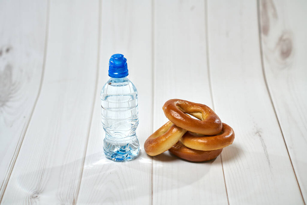        Una bottiglia d'acqua, cracker, asciugatura sullo sfondo di tavole per uno stile di vita sano
.                         - Foto, immagini