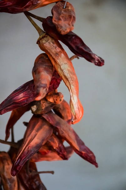 A bunch of dried red hot chili peppers on a gray wall background... - Zdjęcie, obraz