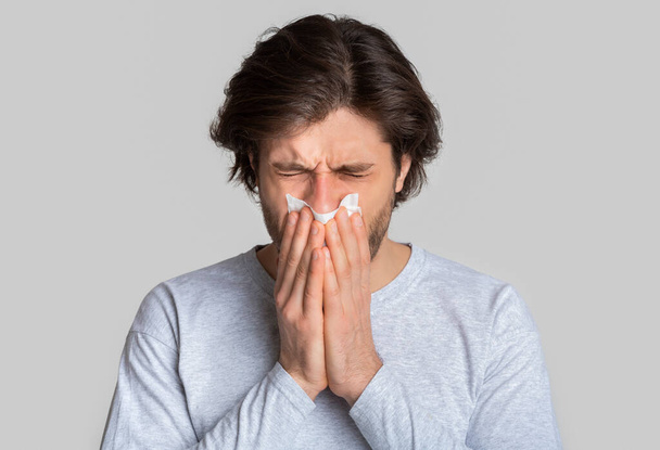 Porträt eines kranken Mannes, der mit Serviette niest - Foto, Bild